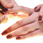 Photo of a beauty therapist holding another woman's hands, examining her nails.